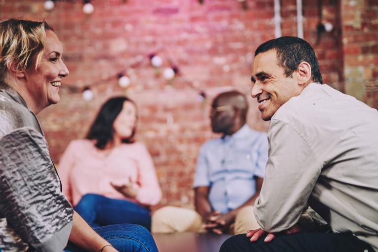 two people talking with two others in the background