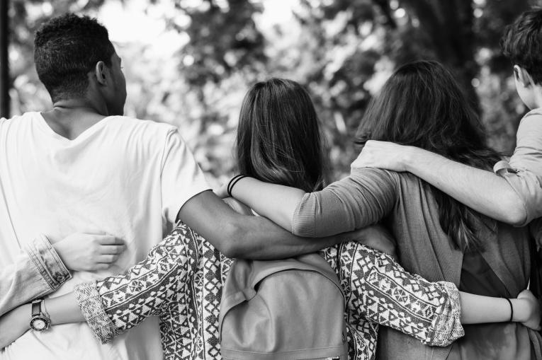 group of young people with arms round each other outside