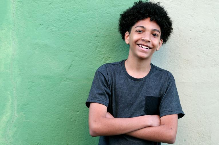 A young boy stood in front of a green wall