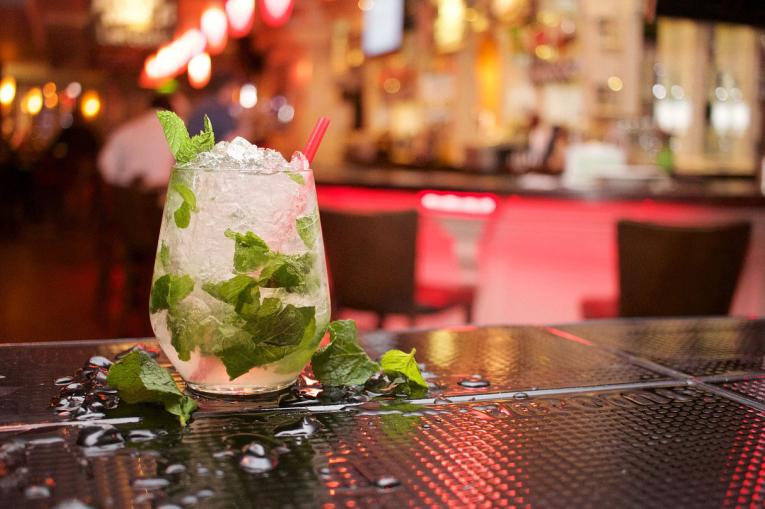 A glass on a bar with a mojito mocktail in it
