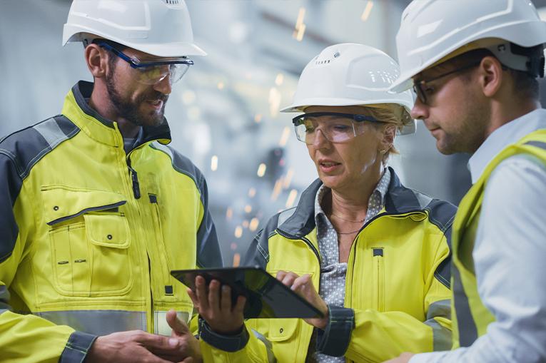 Two men and a woman wearing high visibility jackets and hard hats 