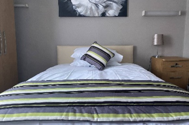 A single bed with a wardrobe and a bedside table on either side.