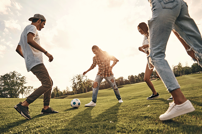 Three young people outside playing football