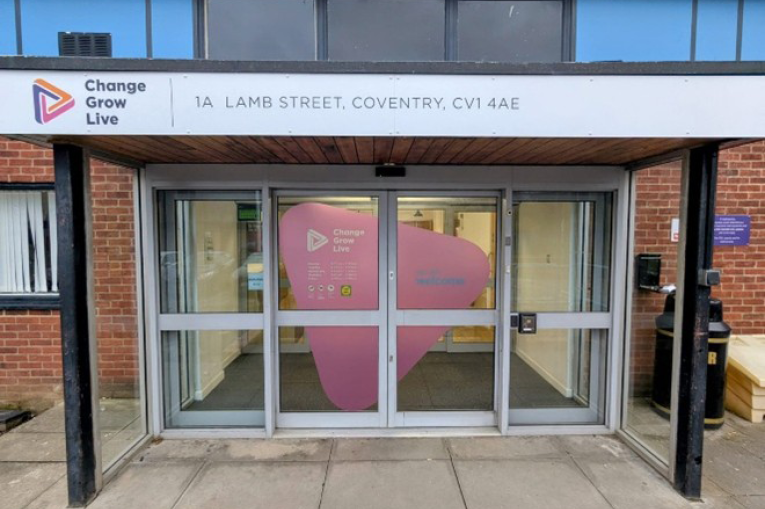 The entrance to a building with double glass doors and a canopy covering the entrance. On the front of the canopy is the Change Grow Live logo and the address of the service