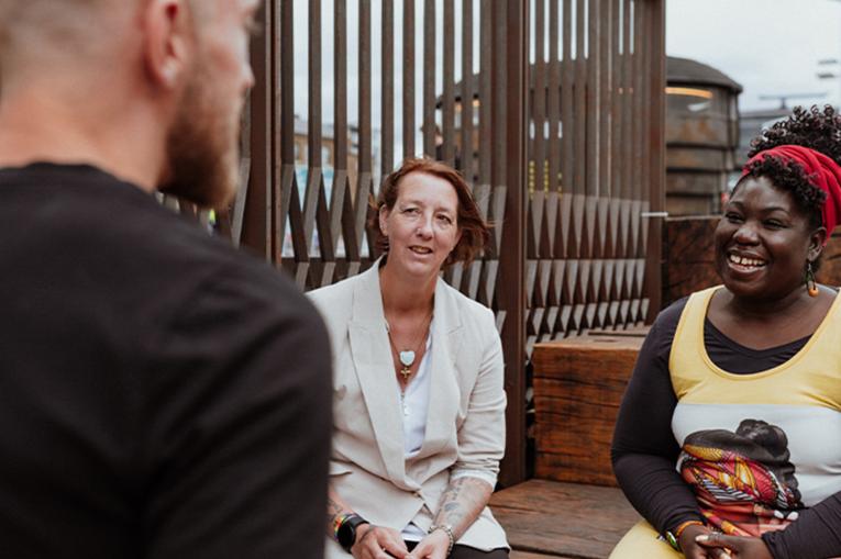 Three people talking to each other, one with their back to the camera