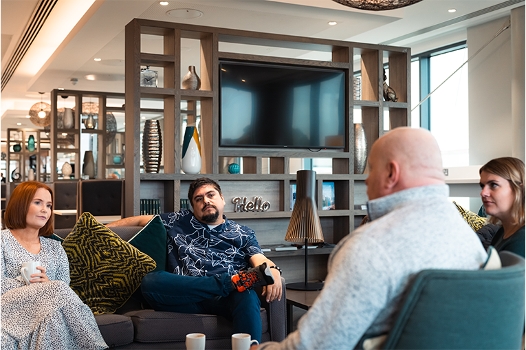 2 women and 2 men sat on sofas engaging in conversation