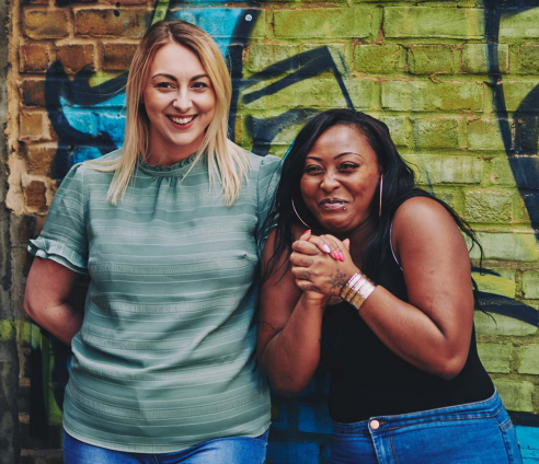two people standing in front of street art laughing
