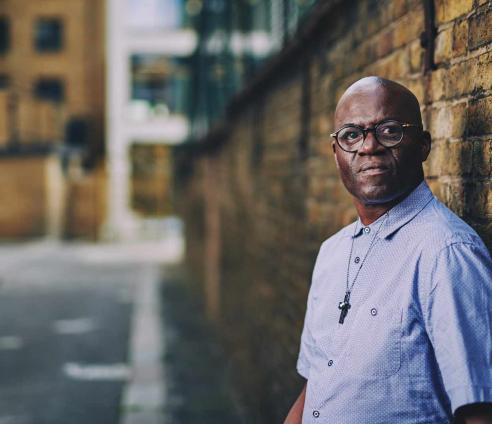 A man is standing next to a brick wall