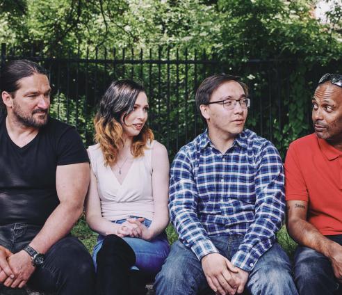 Four people are sitting outside on a bench