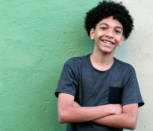 A young boy stood in front of a green wall