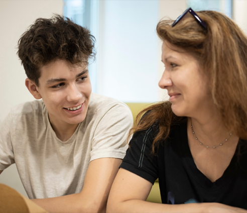 A teenage boy sat talking to a older adult woman