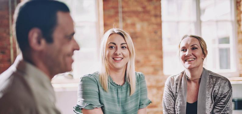 Three people are sitting together smiling