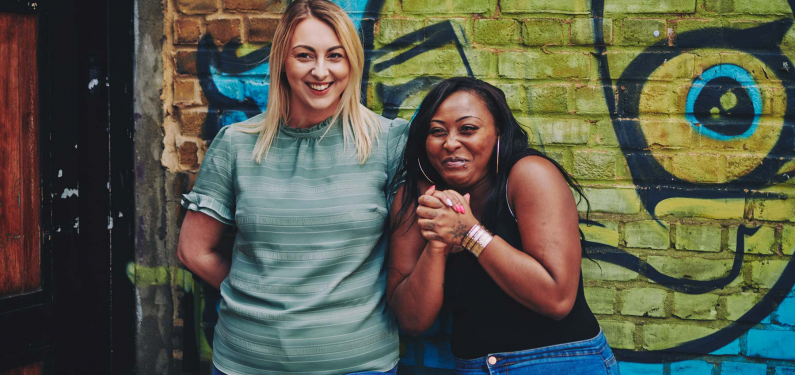 two people standing in front of street art laughing