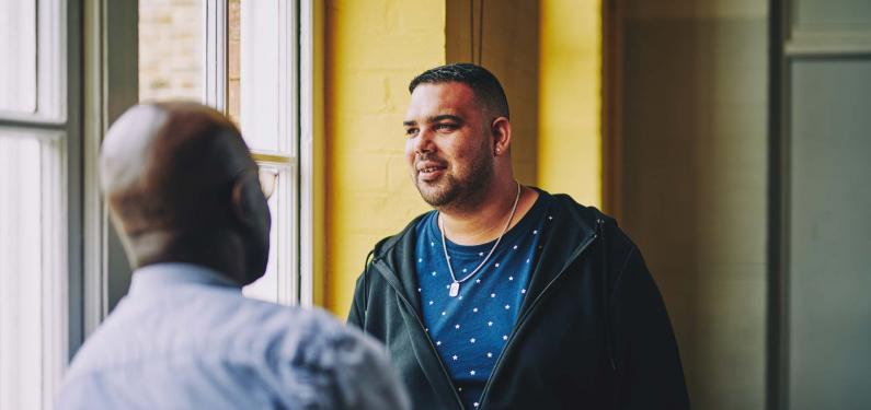 man having a conversation with another man and looking off into the distance