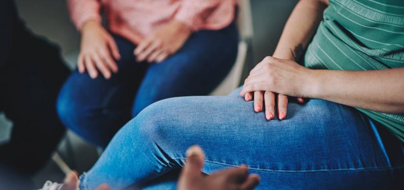 A woman has her hands folded on her lap