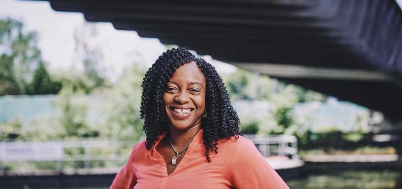 woman standing on a bridge smiling with water in the background