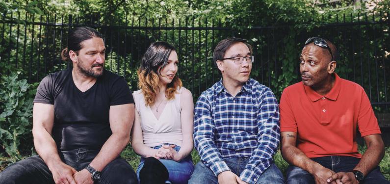 Four people are sitting outside on a bench