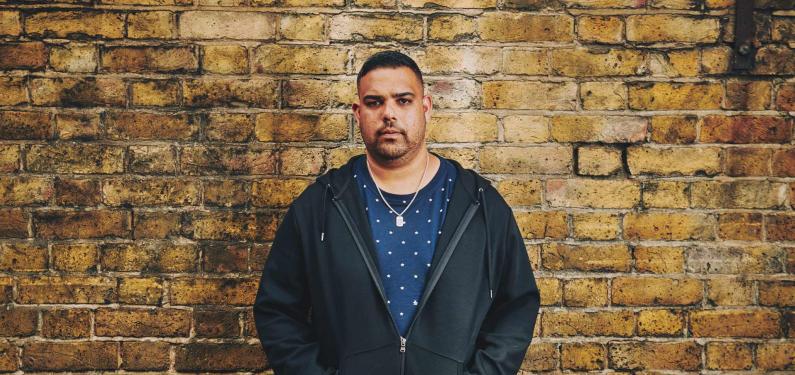 man standing in front of a wall with hands in pockets