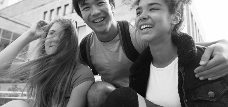 Three young people smiling and hugging