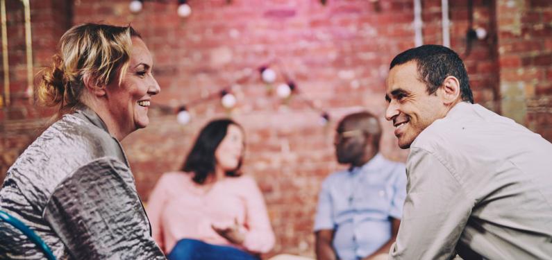 two people talking with two others in the background