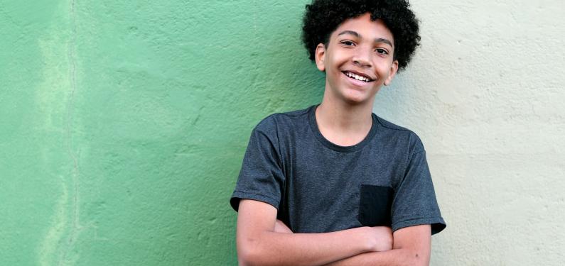 A young boy stood in front of a green wall