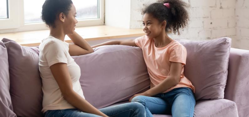 A woman and a child chatting while sat on a sofa