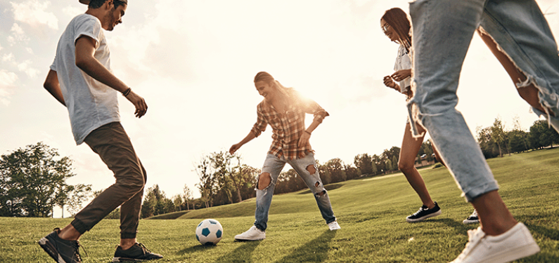 Three young people outside playing football