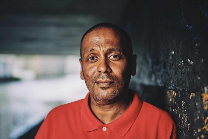 man standing under a bridge looking sincere with a straight face