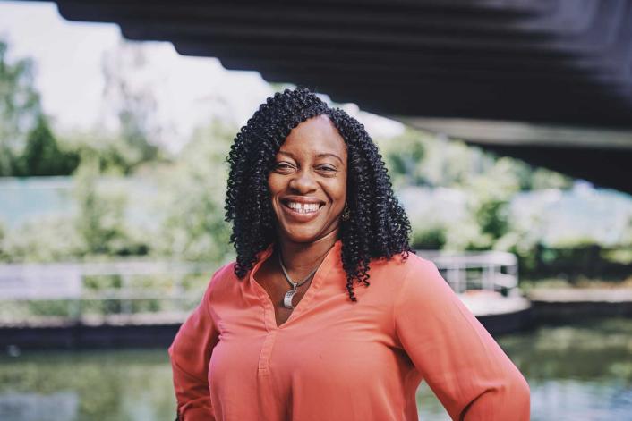 woman standing on a bridge smiling with water in the background