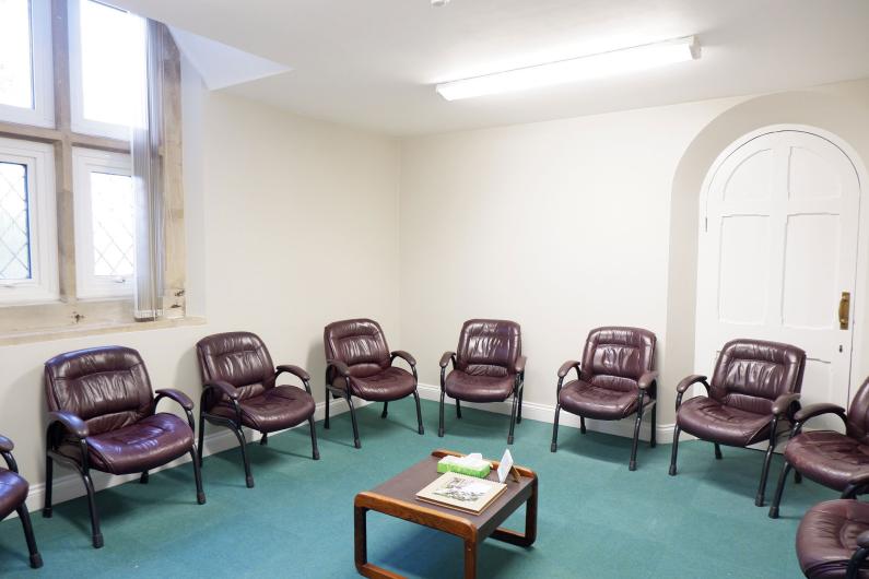 A photo of a group room at Broadway lodge, there are a number of chairs arranged in a circle around the edge of the room