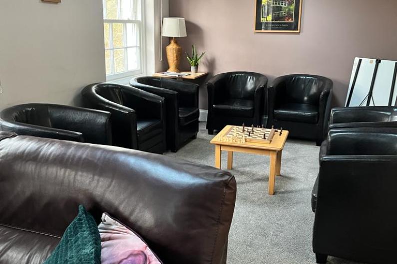 Alpha phase group room - a room with black armchairs centred around a coffee table. There's a large window and wall wall is painted a dusky pink colour
