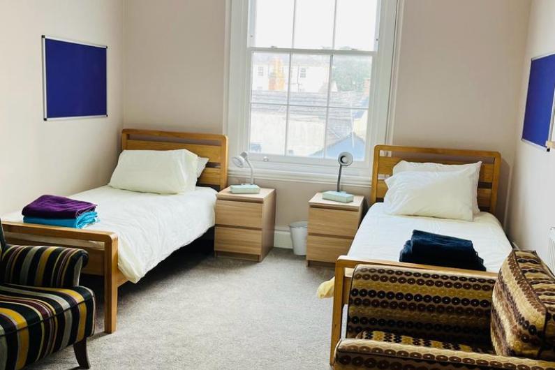 Bedroom - two single beds either side of window. The room has high ceilings and blue art on the walls and sofas at the end of each bed