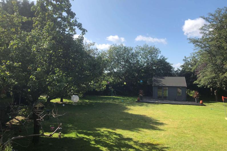 A photo of a big garden. There is plenty of open grass space and trees surrounding it. 