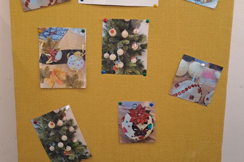 A photo of a notice board with pictures stuck to it of previous crafts people have made