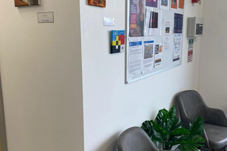 An image of a waiting room. There are pictures up on the wall and a couple of chairs for people to sit in. 