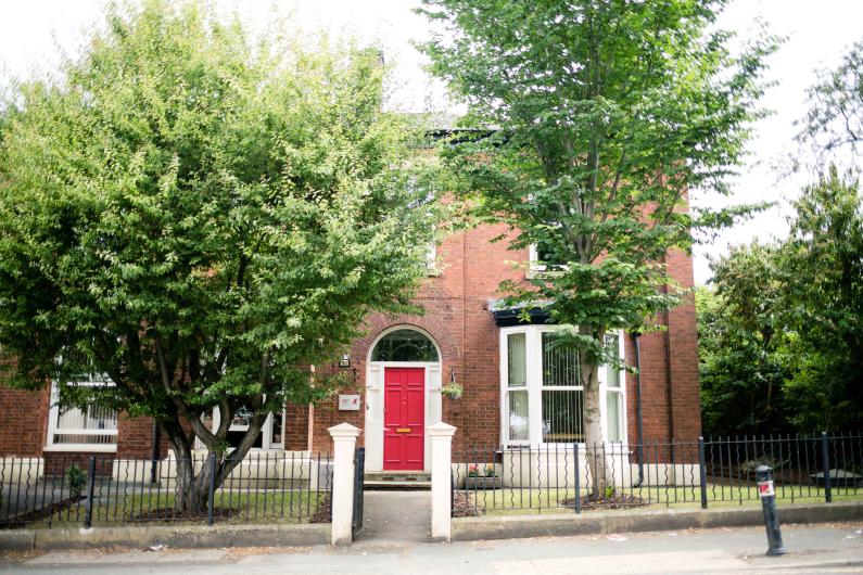 Leigh bank - a red brick building with a red front door on a tree-lined street
