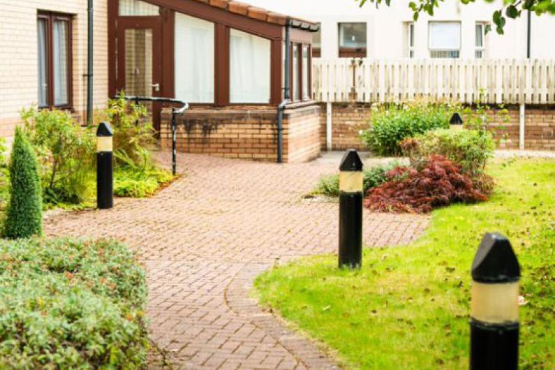 The garden at Phoenix Futures - the building is in the background, there is a wiggly path in the foreground lined with grass and solar lamps