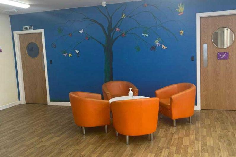 Reception area - a room with four orange tub chairs, a blue wall and doors either side of the chairs