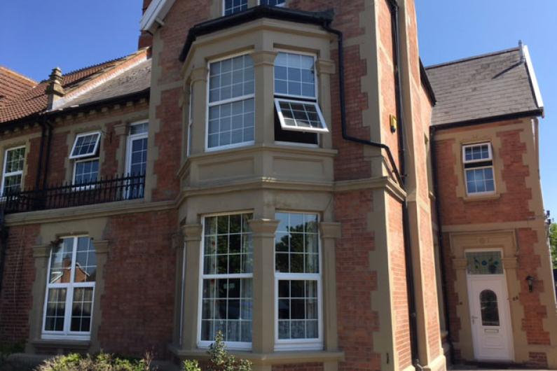 The outside of a Victorian style house. It is two storeys with bay windows and red bricks. The front door is to the right and there are a number of windows along the front of the building. 