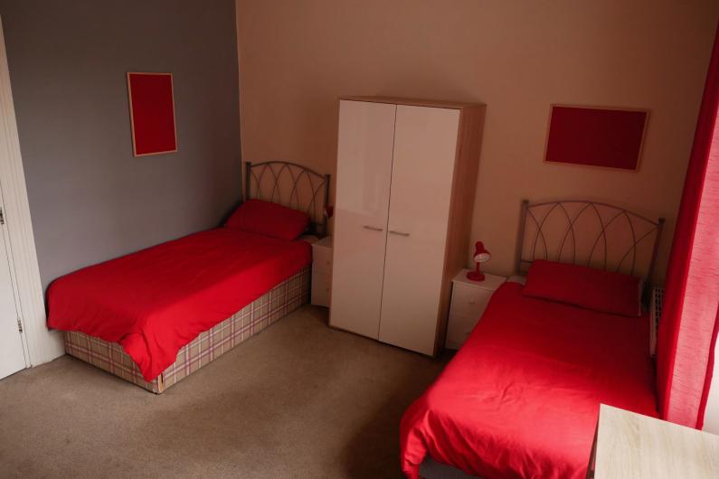 Western Counselling bedroom - a room with two single beds with red bedding and a white wardrobe