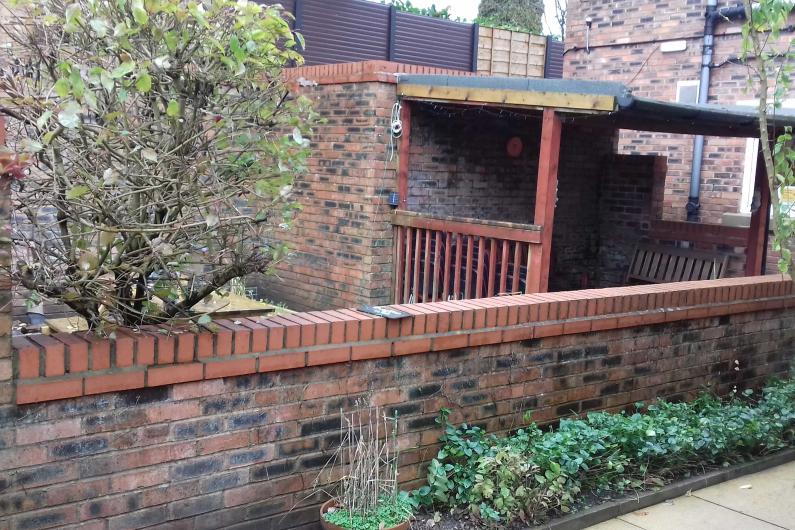 Leigh bank - garden. A patio area with a shelter, a brick wall a tree and some plants