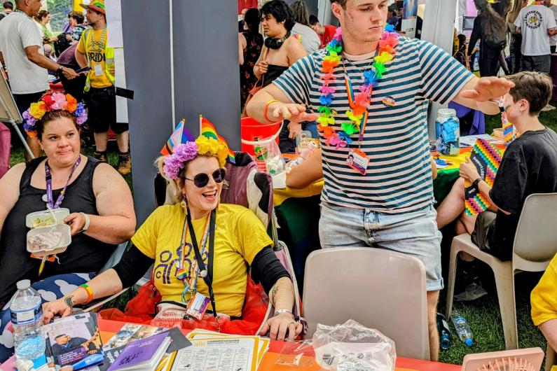 A colourful photo of people stood behind a stall