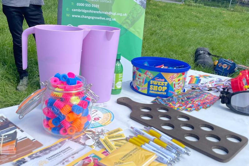 A Table with a tub of sweets, drink pitchers and leaflets on it