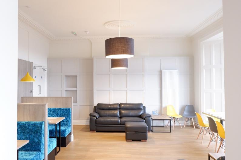 A group room with sofas, white walls and wooden floors