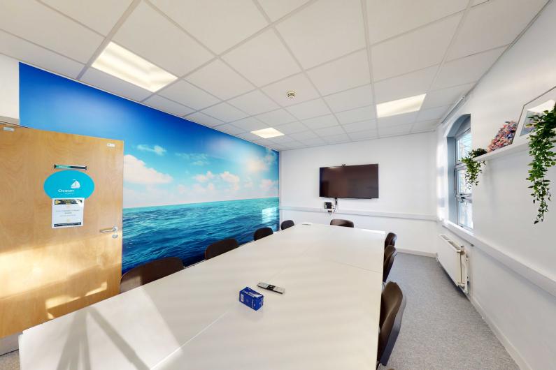 Houghton Health Centre - a modern group room with a large white table, blue mural and TV screen.