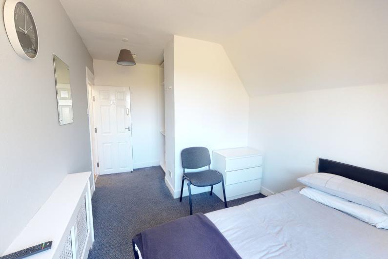 Liberty House Bedroom. - A room with a singe bed, white walls and grey carpet.