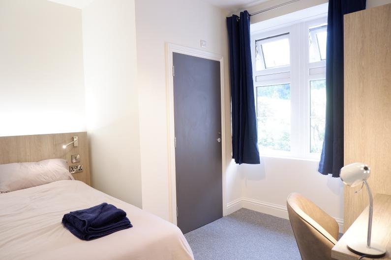 A bedroom with white bedsheets, a window and a door