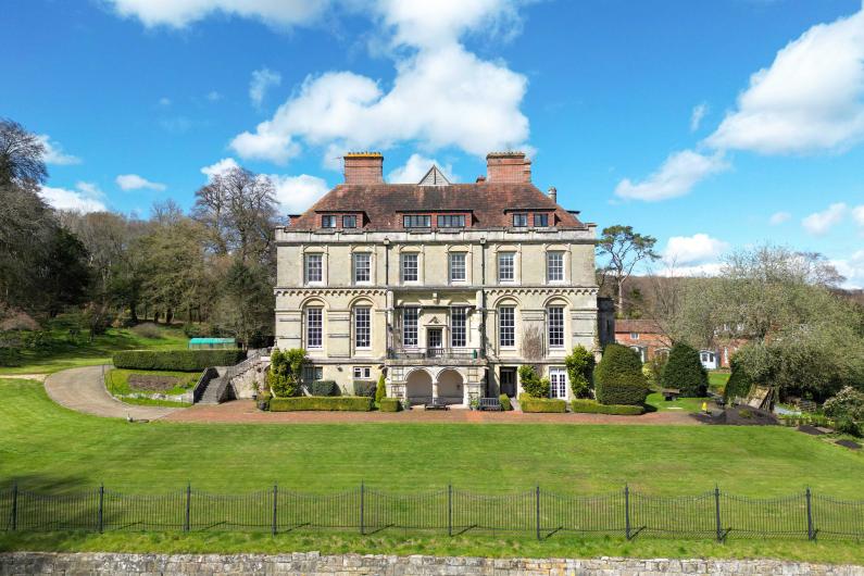 Clouds house - national detox and rehab framework - the outside of the building - a large white detached countryside house with grass surrounding it, blue sky and clouds