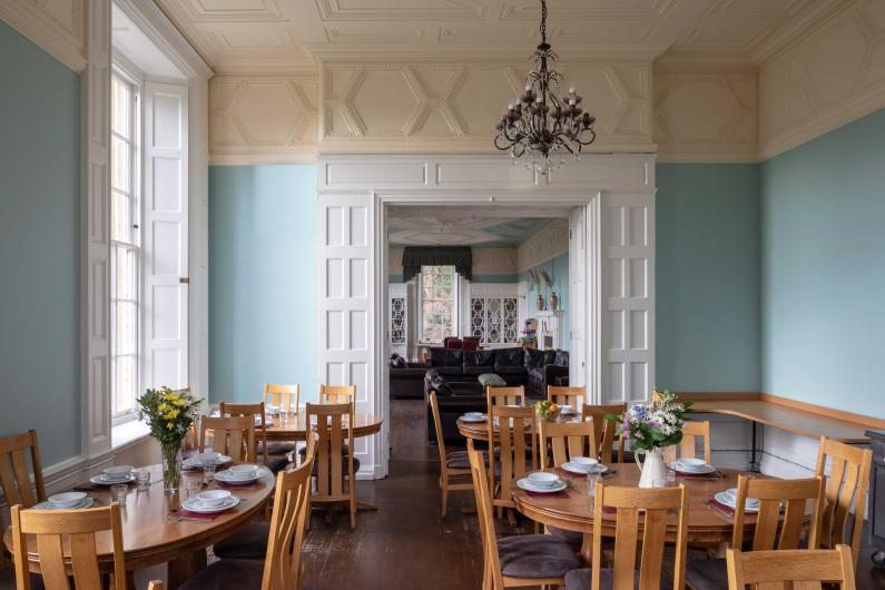 Clouds House dining room - with high ceilings, wooden chairs an sky blue walls