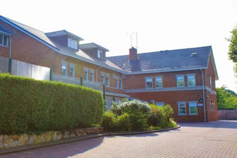 The outside of a building with hedges in front of it.